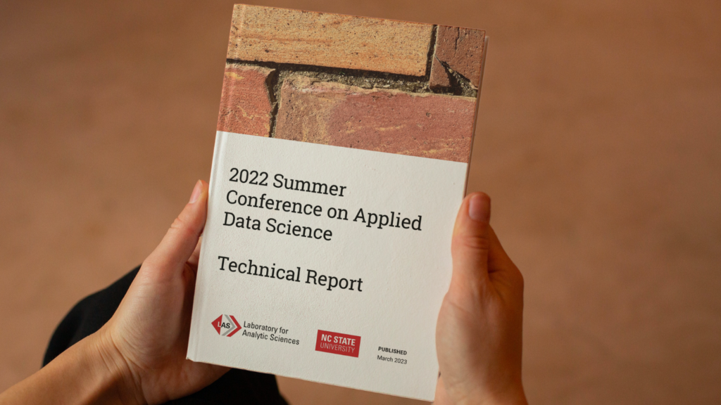 Hands holding a copy of the technical report.