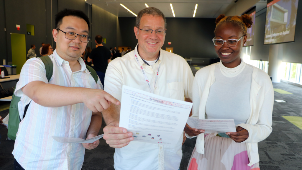 Three people looking at a TLDR prototype on a single sheet of paper.