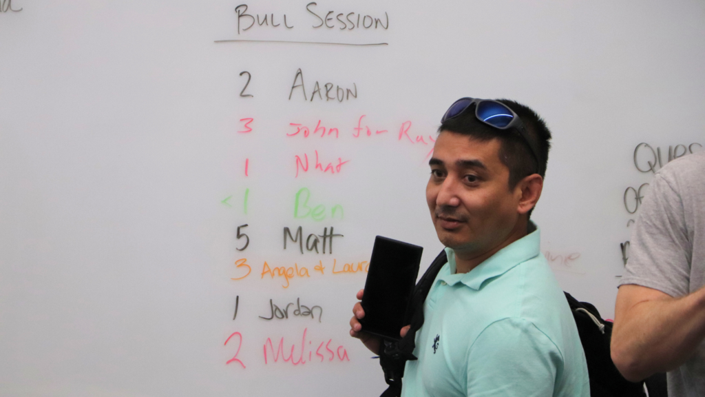 A man in front of a whilte board with a list of names