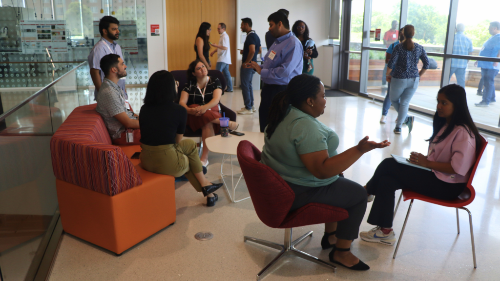 A large group of people standing and sitting in groups of 2 or 3, engaged in conversation