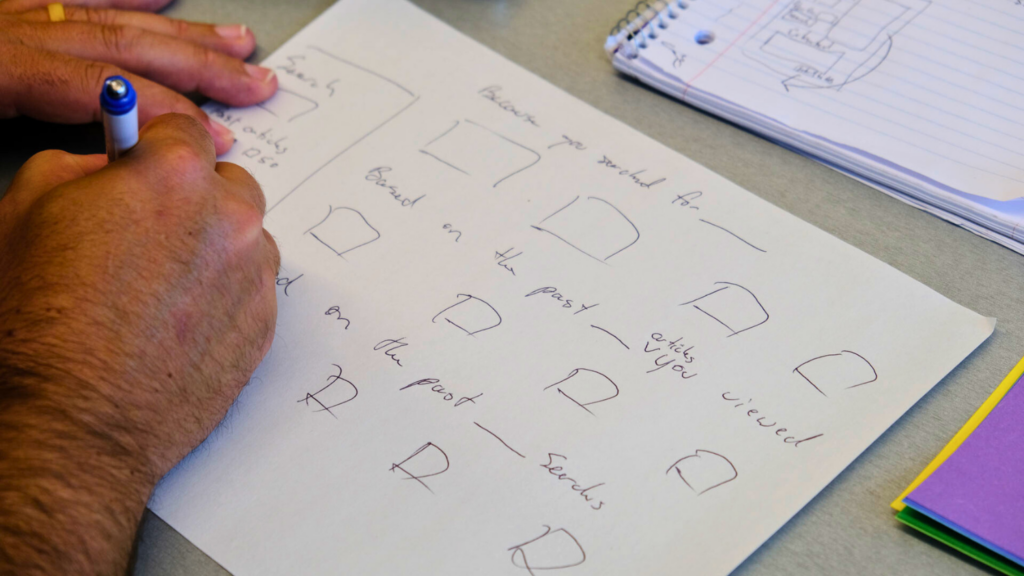 A man's hand, writing on paper: "Because you searched for blank" and "Based on the past articles you viewed"