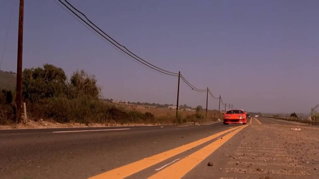 A red car on the horizon of a highway