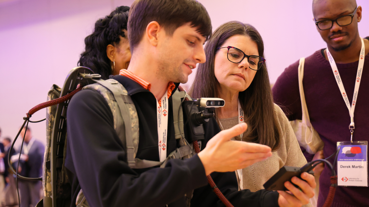 A student demonstrates technology to onlookers.