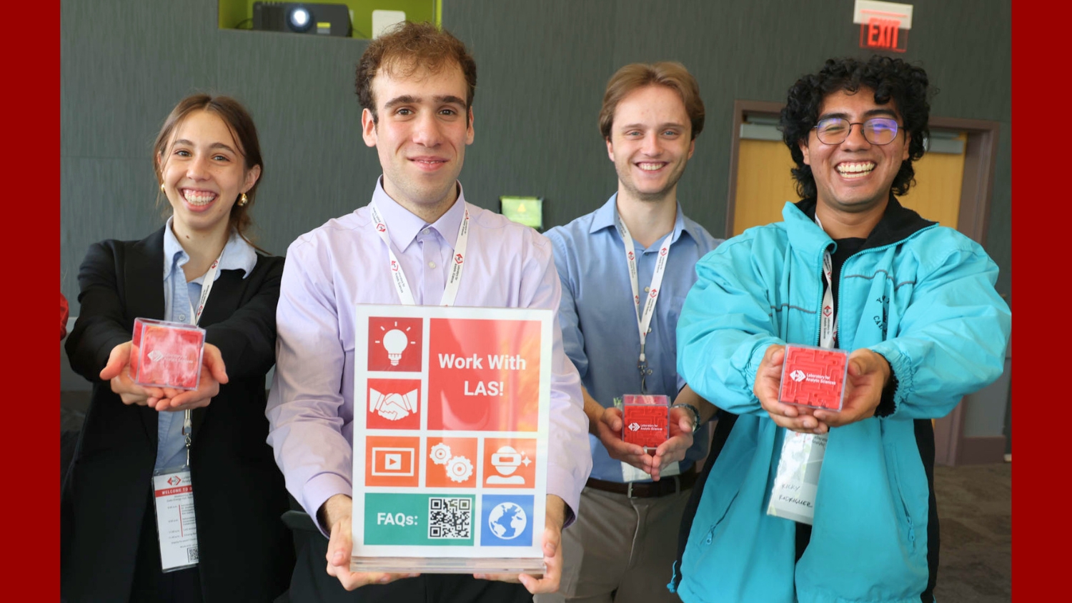Four smiling students hold maze puzzles branded with the LAS logo