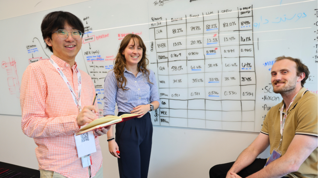 A group of three participants at a whiteboard.